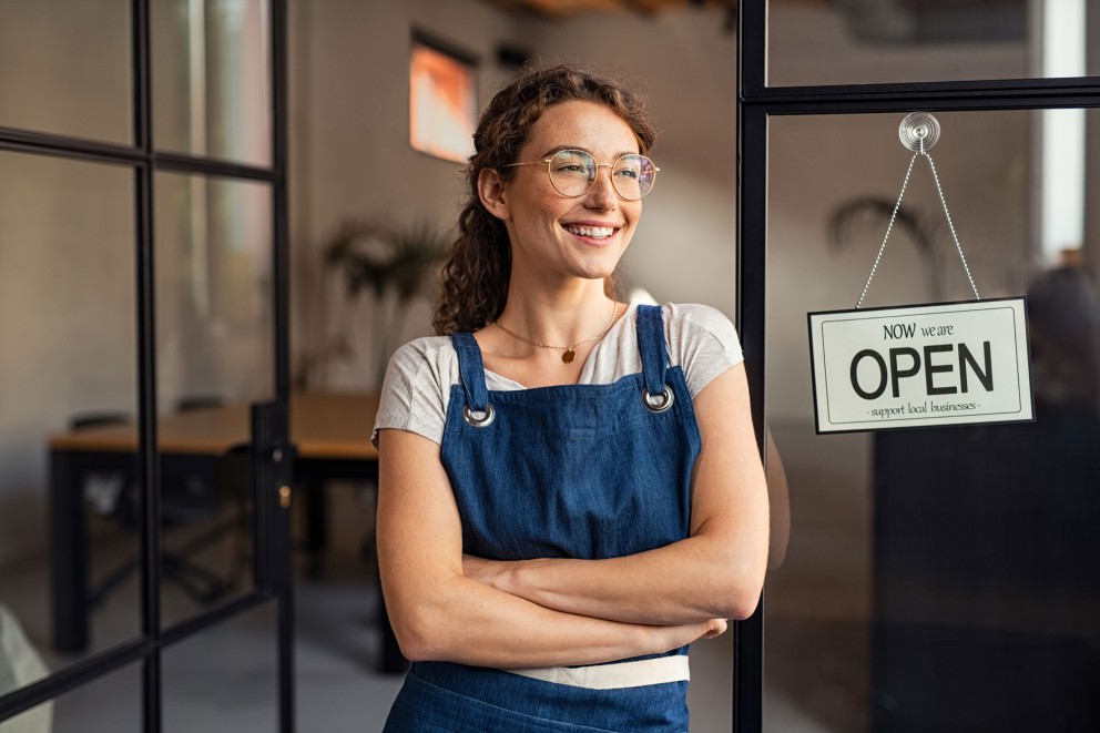 shop owner beside an open sign